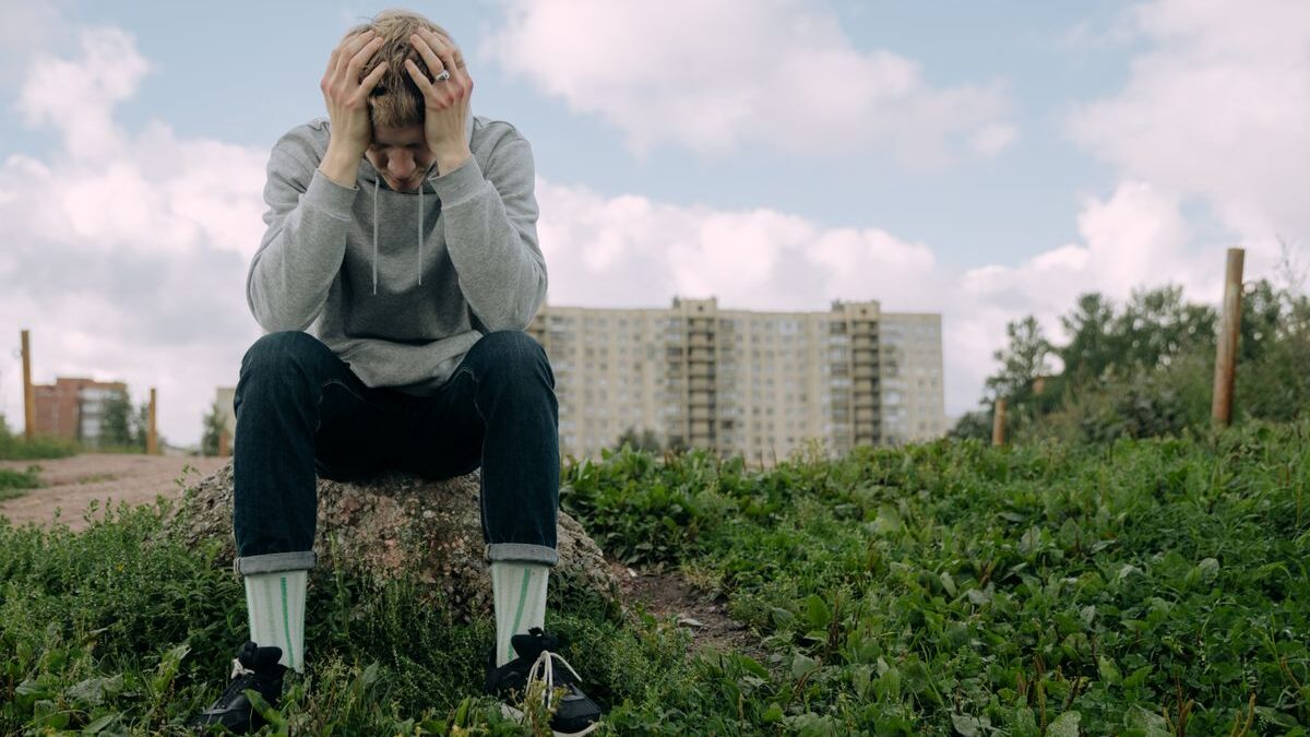 Teen boy with head in hands.