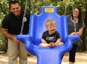down syndrome baby on swing with parents