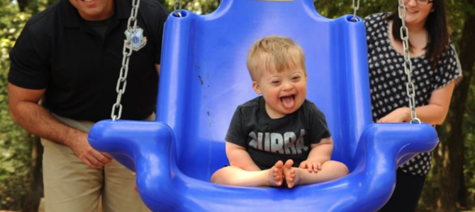 down syndrome baby on swing with parents