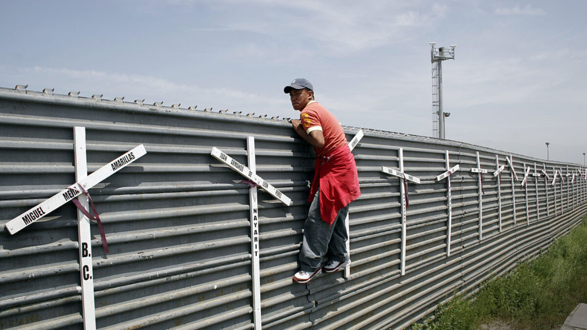 Migrant climbing a border fence