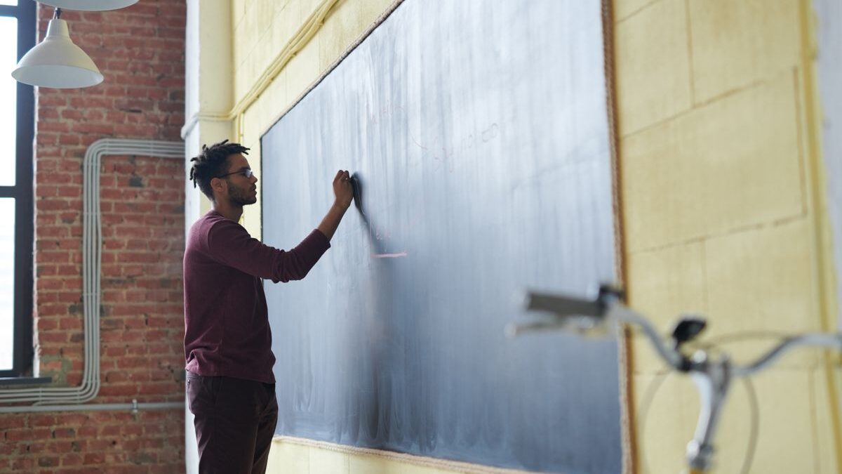 Man writing on a chalkboard in a classroom