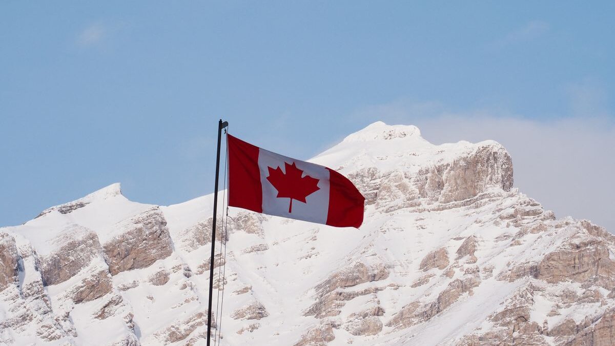 Canadian flag with mountains in the background.