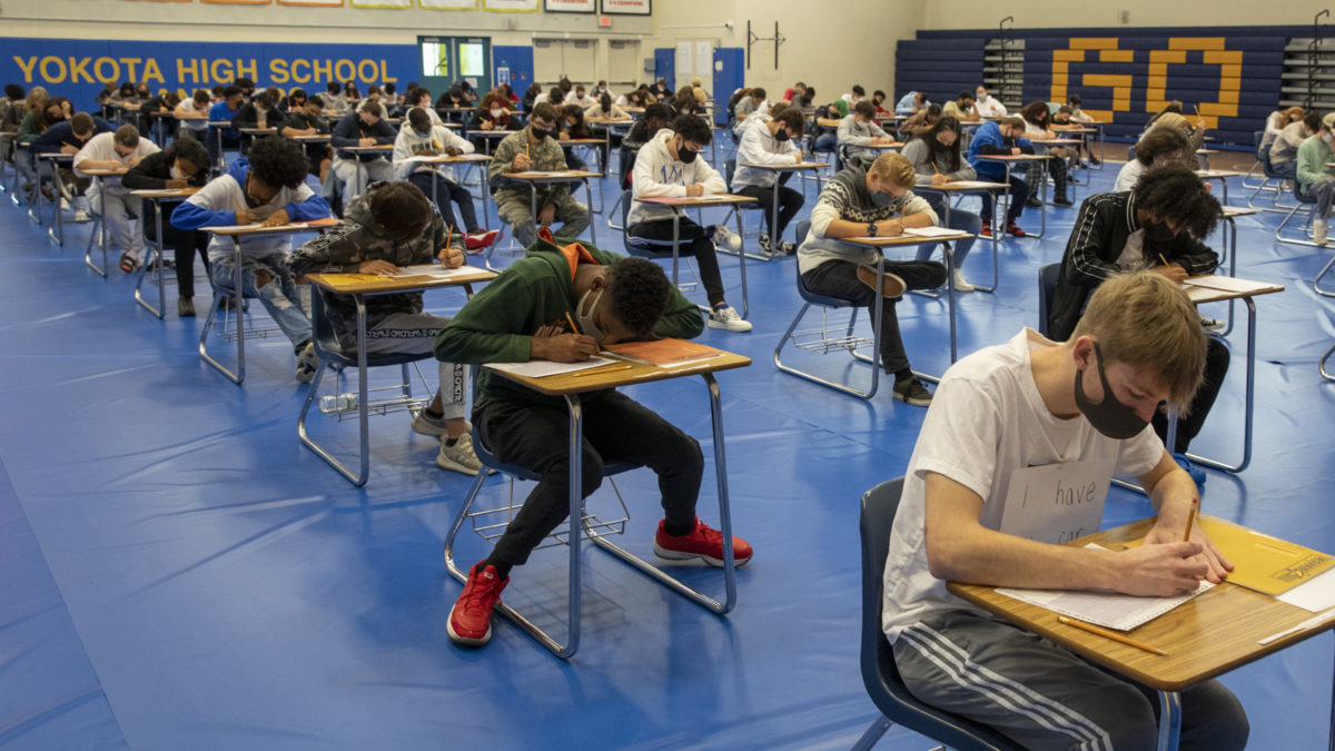 students taking test at desks in gym