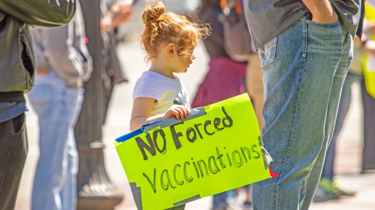 Child holding "No forced vaccination" sign
