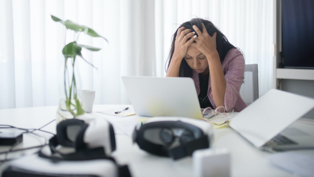 stressed woman laying head on desk at work