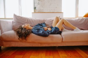woman laying on couch in pain holding her stomach