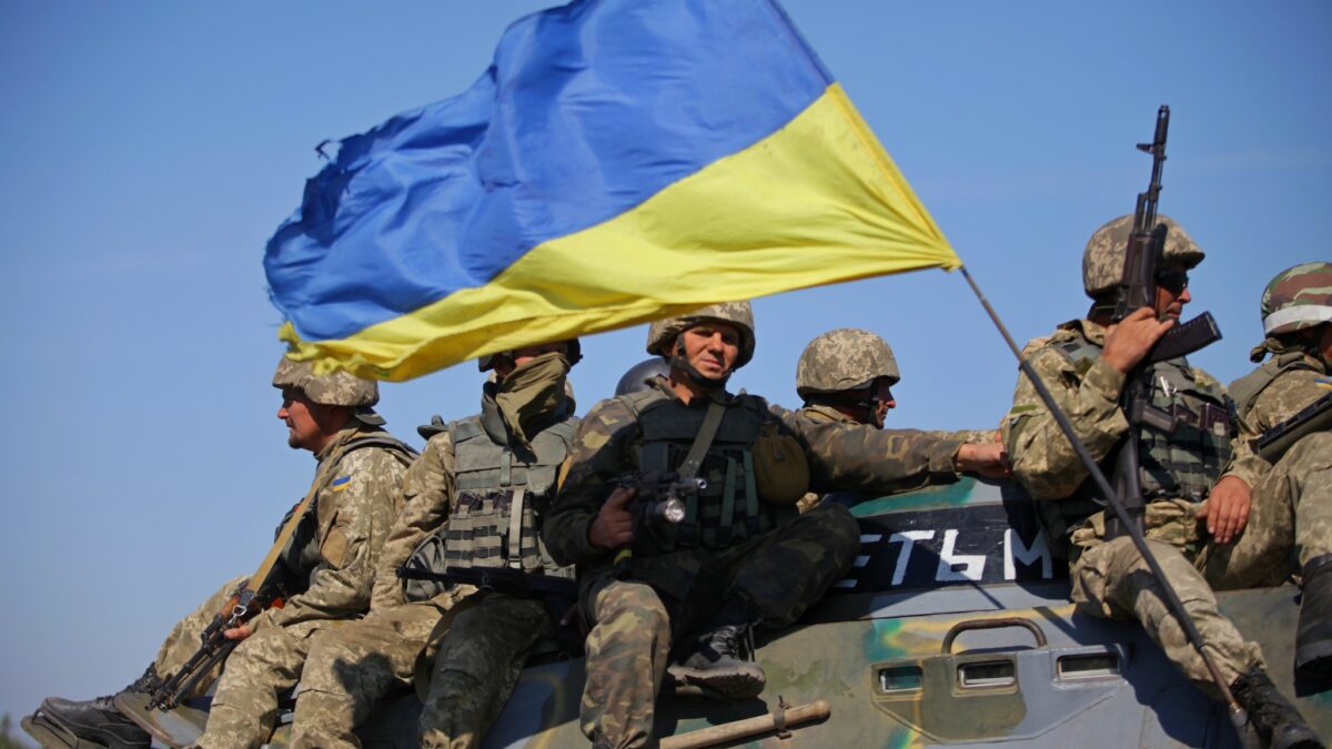 soldiers sitting on tank with Ukrainian flag