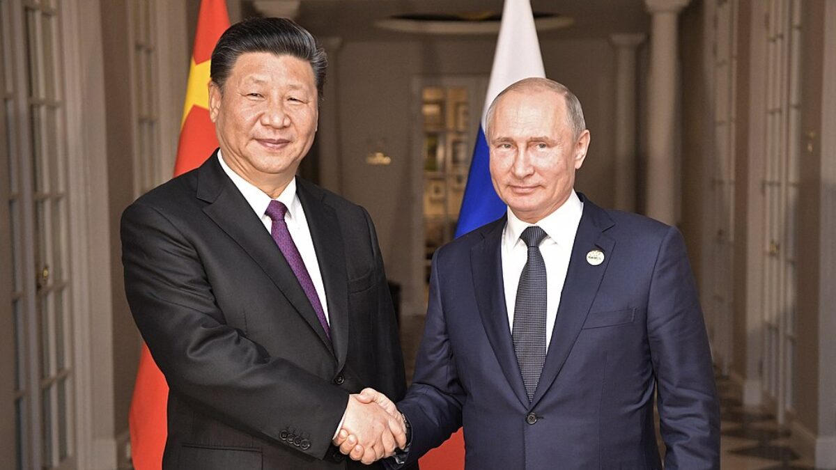 Two men shaking hands in front of flags