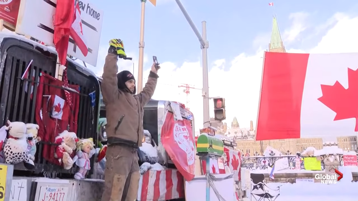 Canadian protester stands in front of trucks