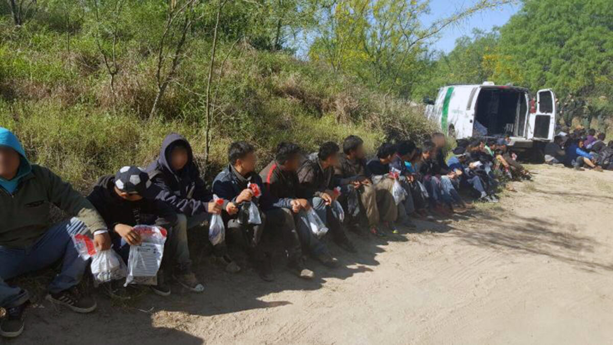 border crisis with migrants sitting on the ground