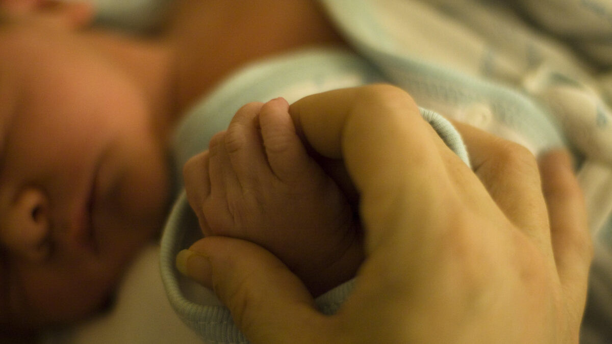 holding hands with a newborn baby