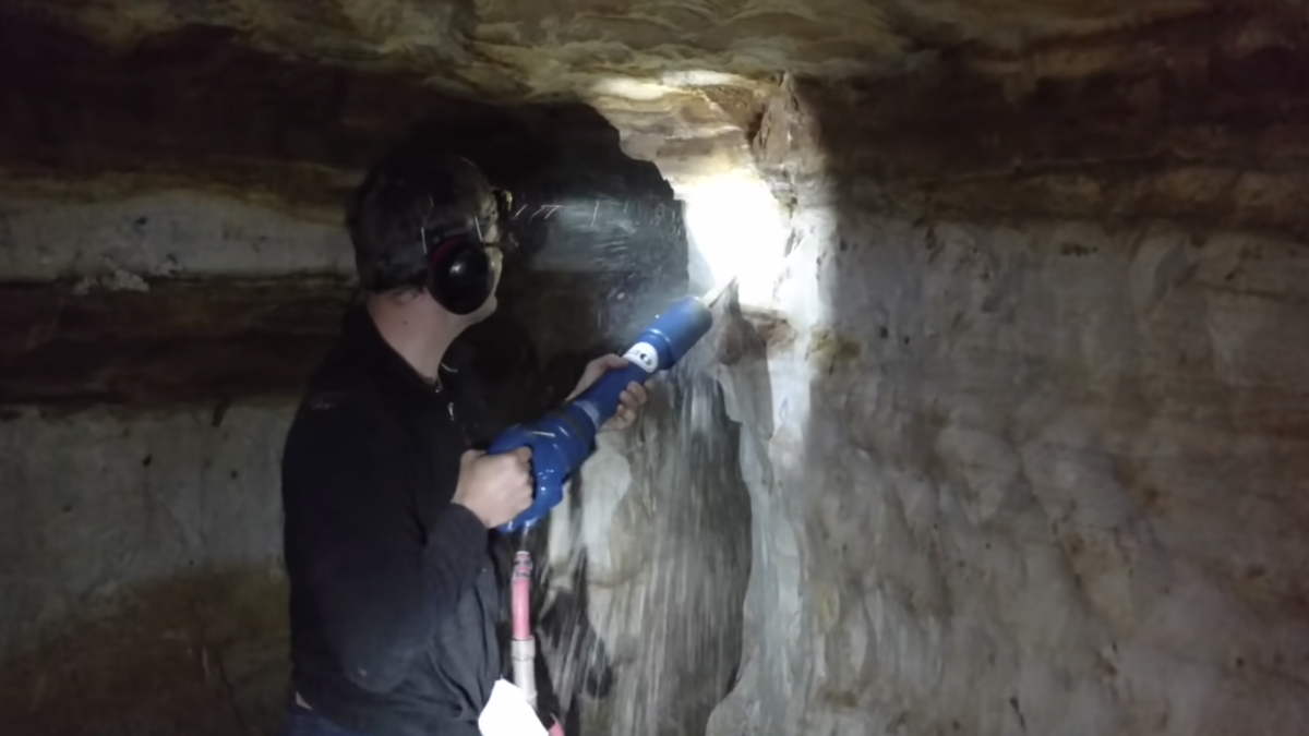 man with jack hammer carving out underground tunnel