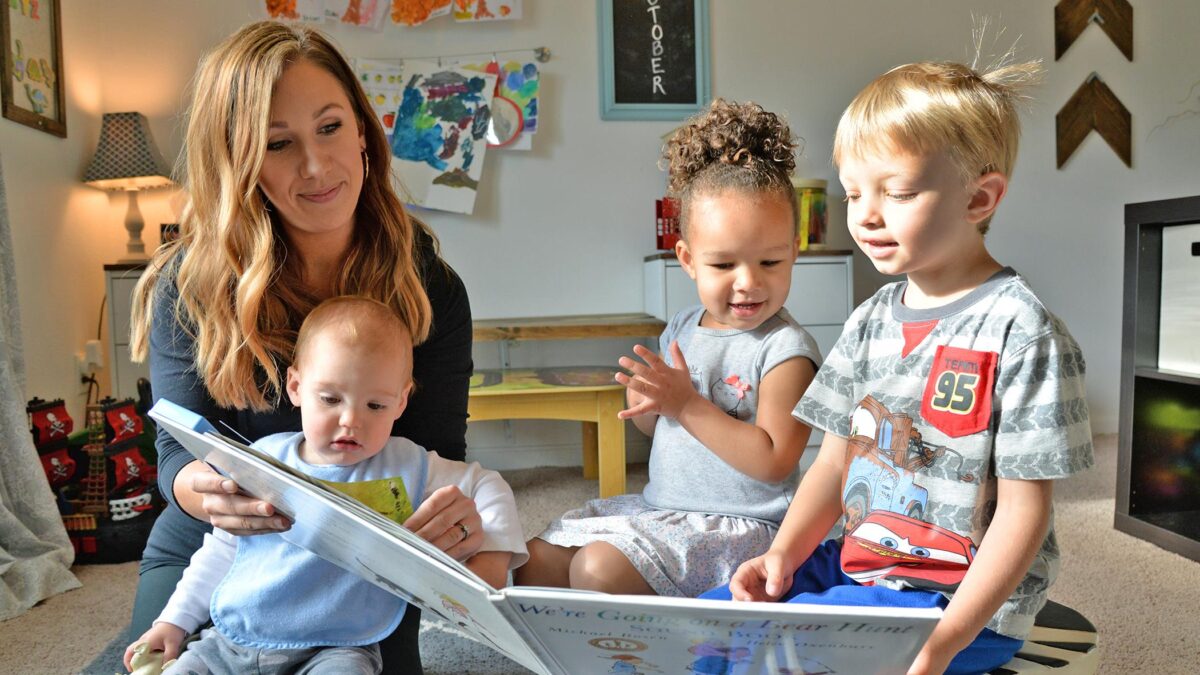 stay-at-home mom providing child care to three kids with book