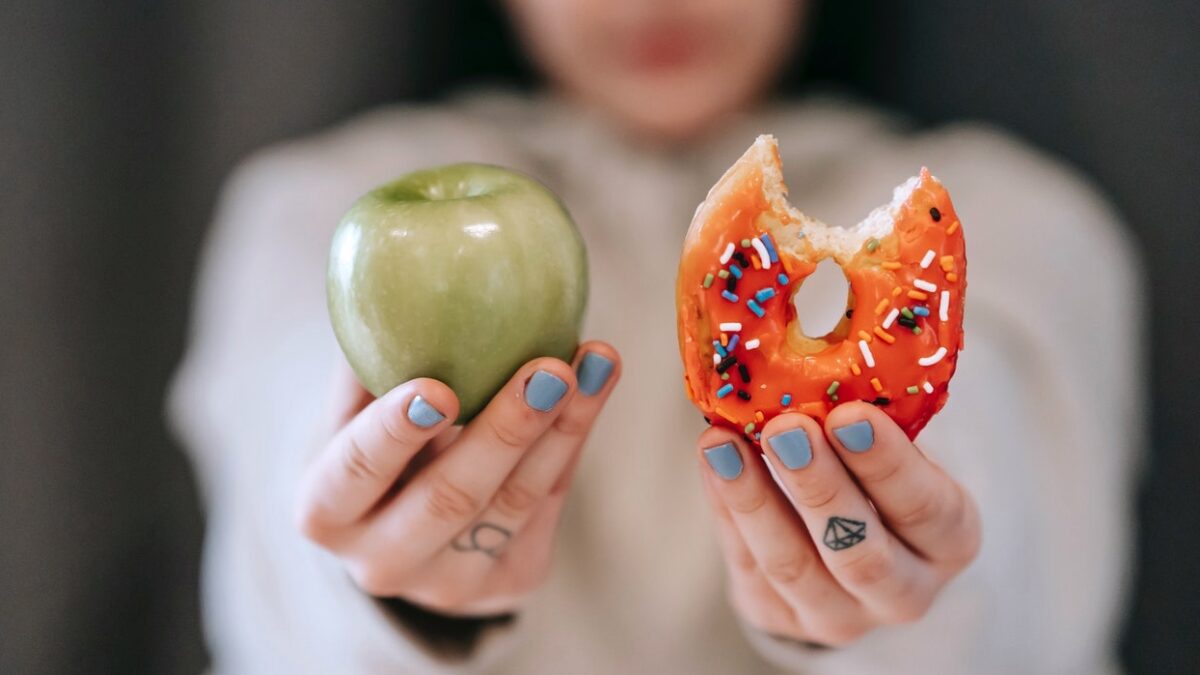 body positivity or eating well? woman holding apple and donut