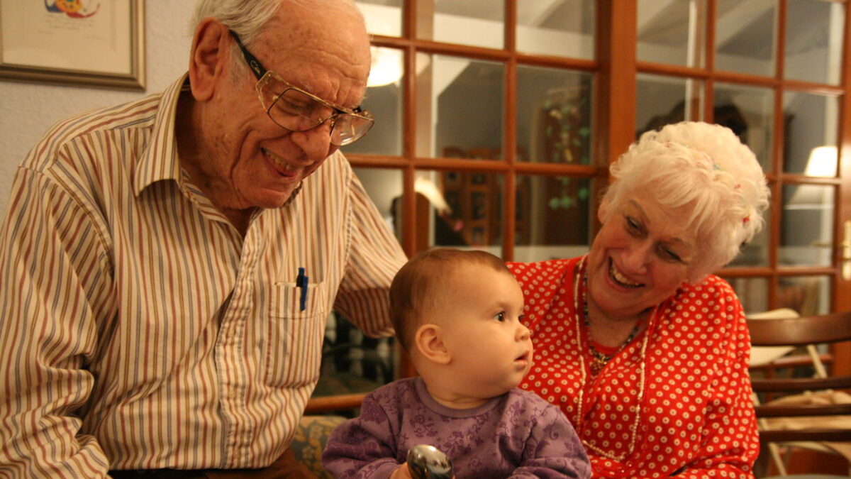 great grandparents sit with and smile at baby