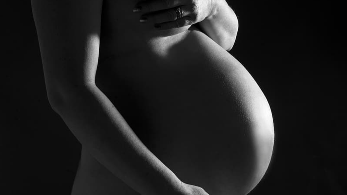 naked pregnant woman holding her belly