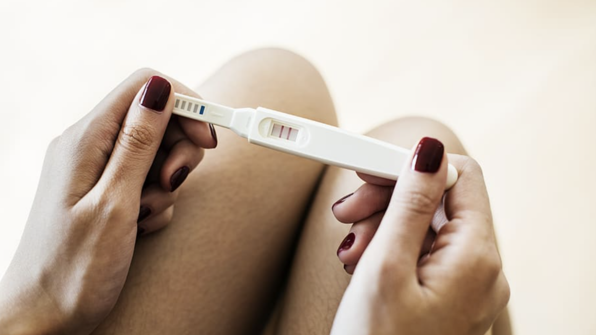 woman's hands holding positive pregnancy test