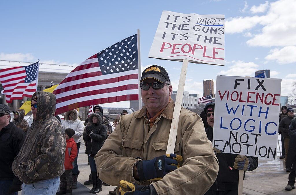 men at protest holding sign wearing nra hat