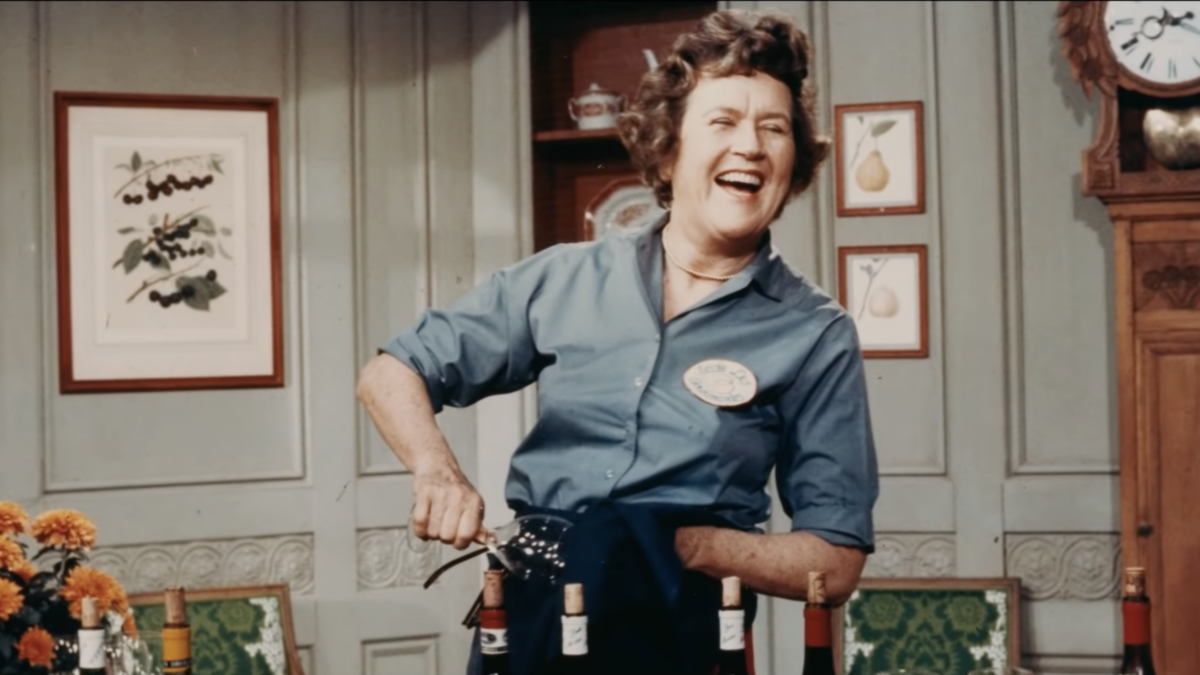 Julia child laughing while opening bottle of wine