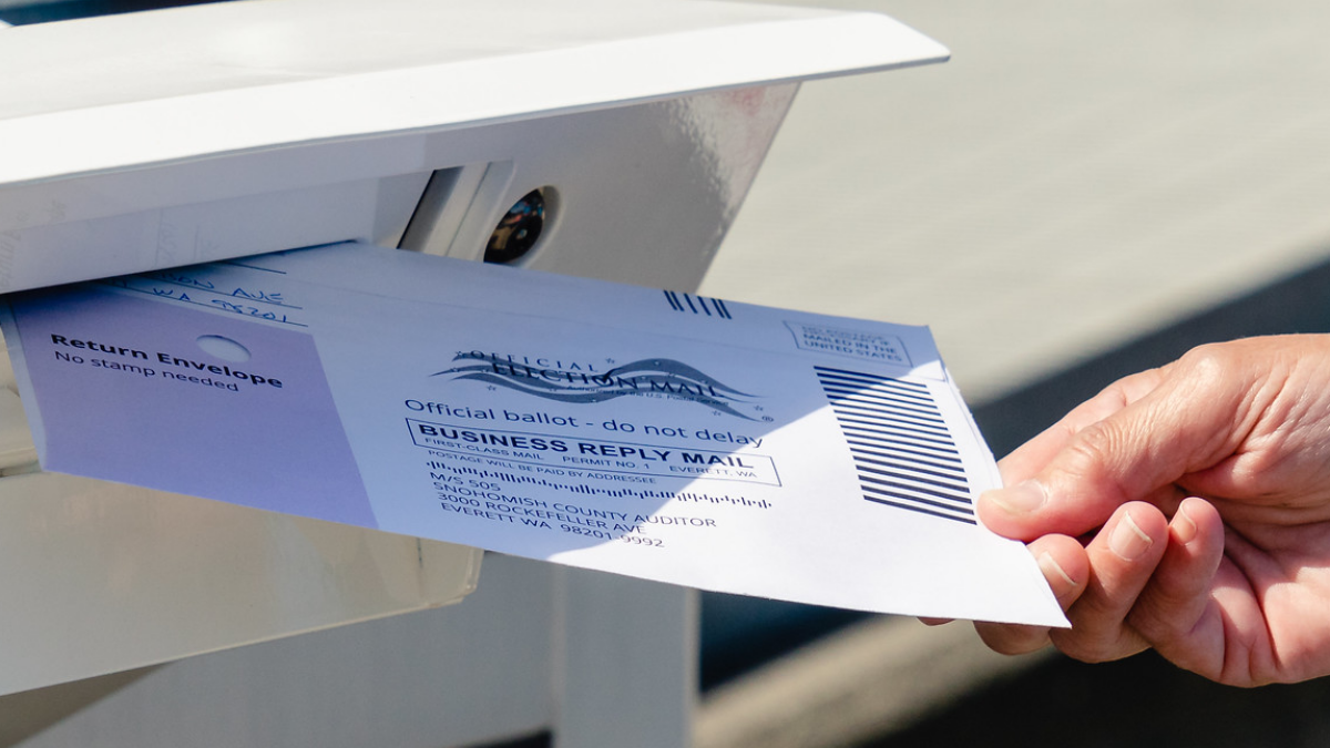 Hand drops ballot in mailbox