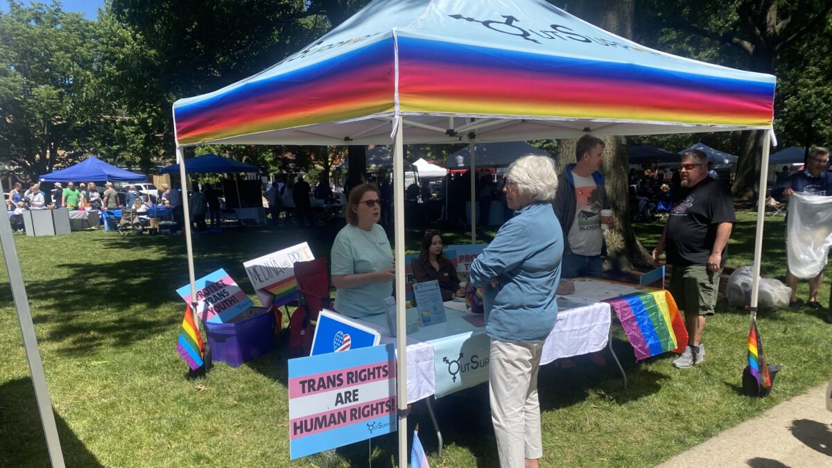 man stands at pride tent outside at farmers market