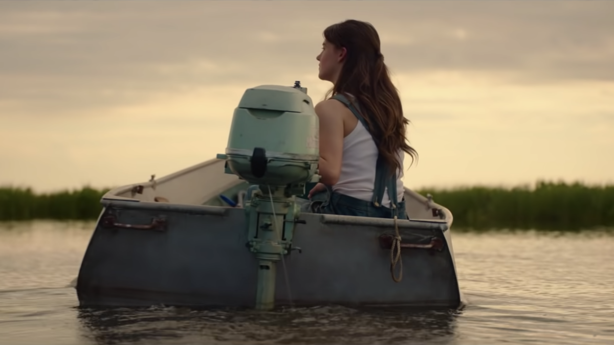 girl driving boat with single motor through a marsh