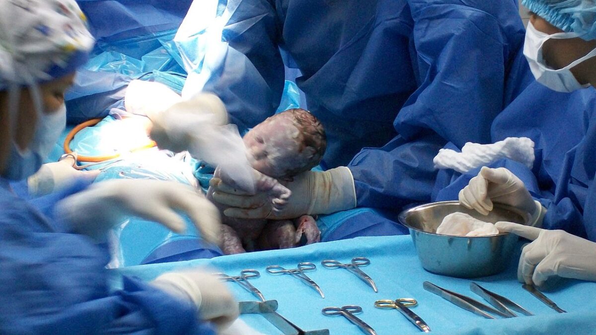 Doctors delivering baby via C-section in operating room