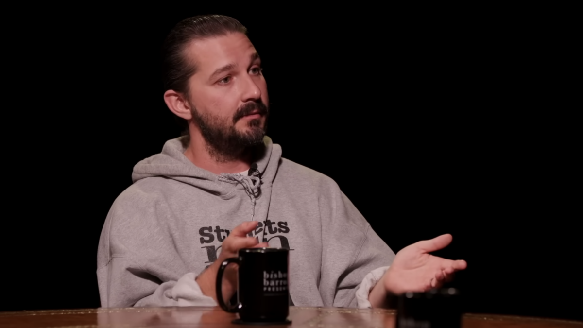 Shia LeBeouf talking in podcast interview sitting at table