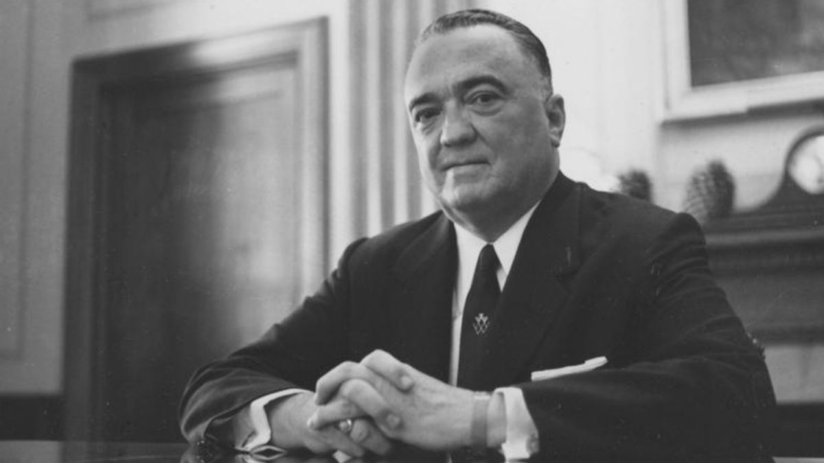 black and white photo of Hoover at his desk with hands folded