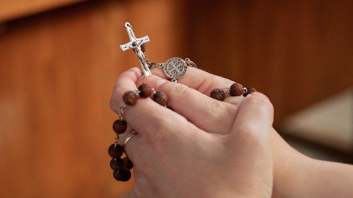 praying hands holding rosary