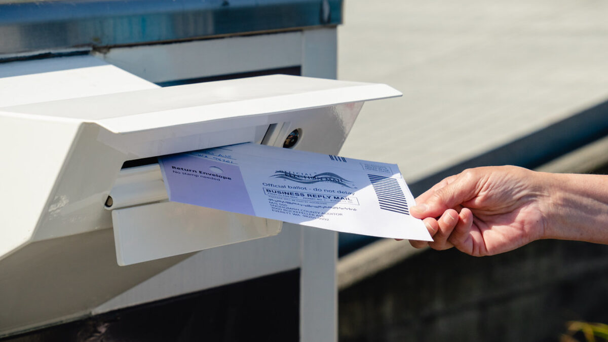 hand drops off ballot in mail box
