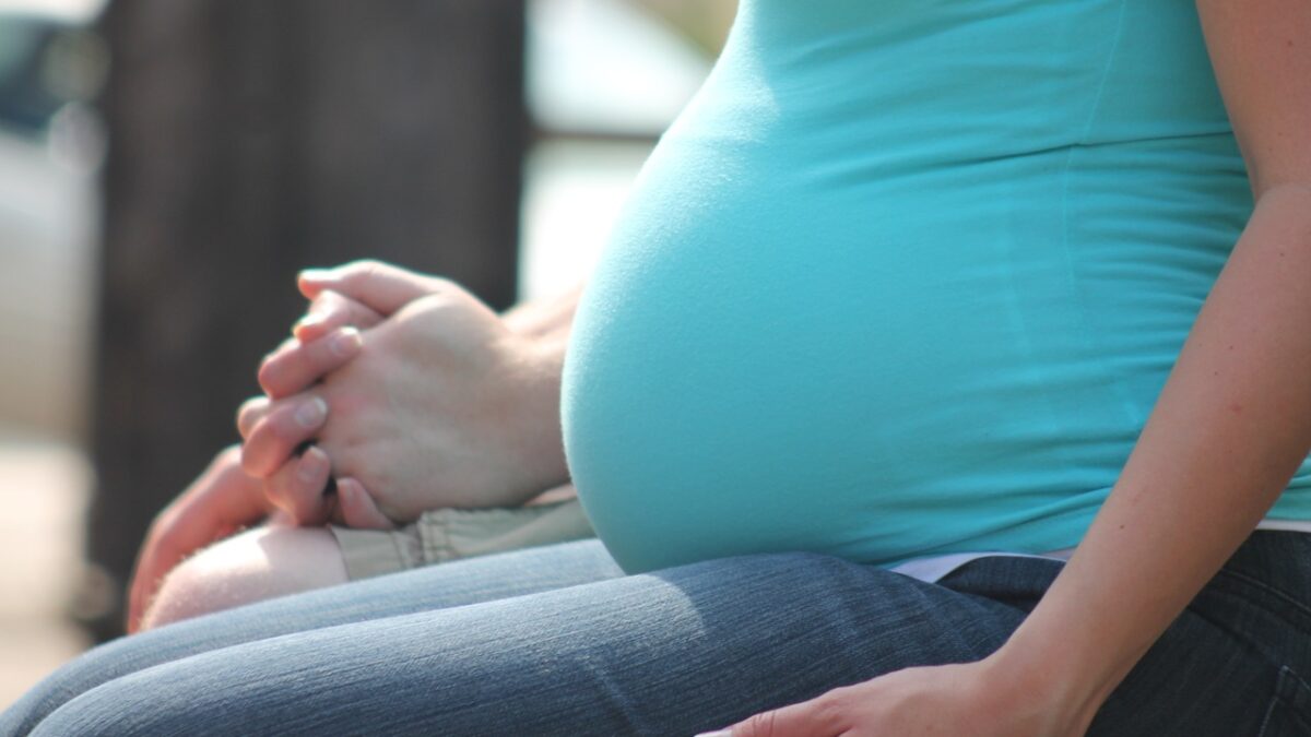 pregnant woman holding hands sitting on bench