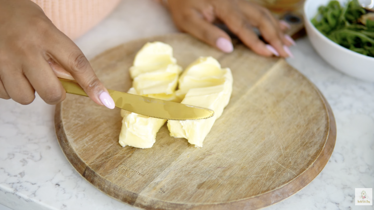 sticks of butter being spread on wooden cutting board