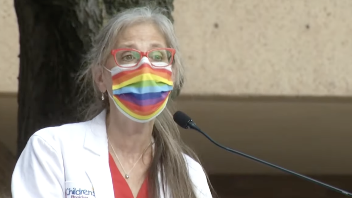Doctor wearing rainbow mask speaking into mic at press conference
