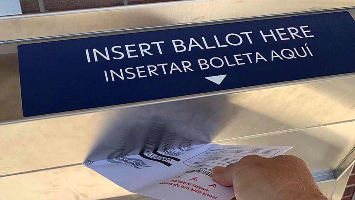 person putting a ballot in a drop box