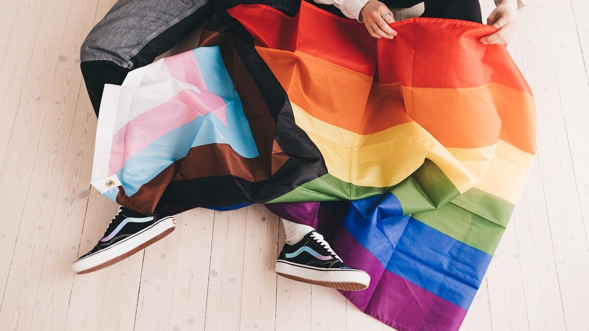 lgbt flag draped over kid with shoes sticking out the bottom