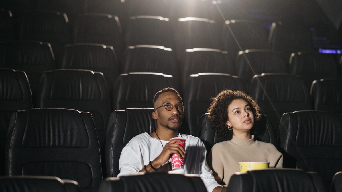 two adults eating popcorn in movie theater