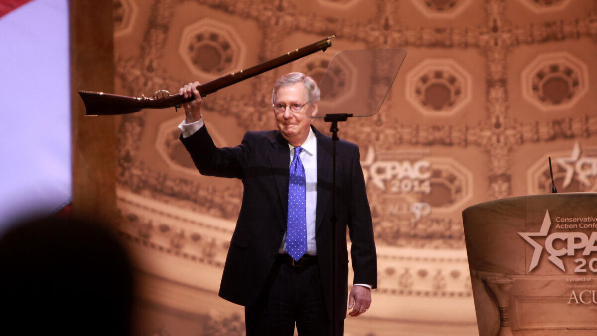 Mitch McConnell holding a gun onstage