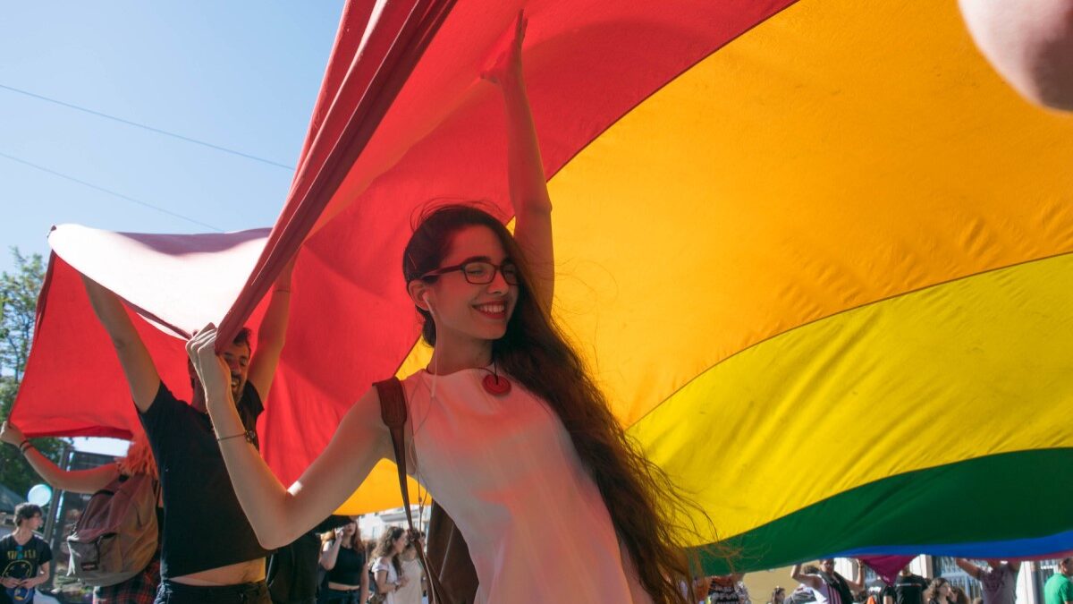 girl helping to hold huge gay pride flag