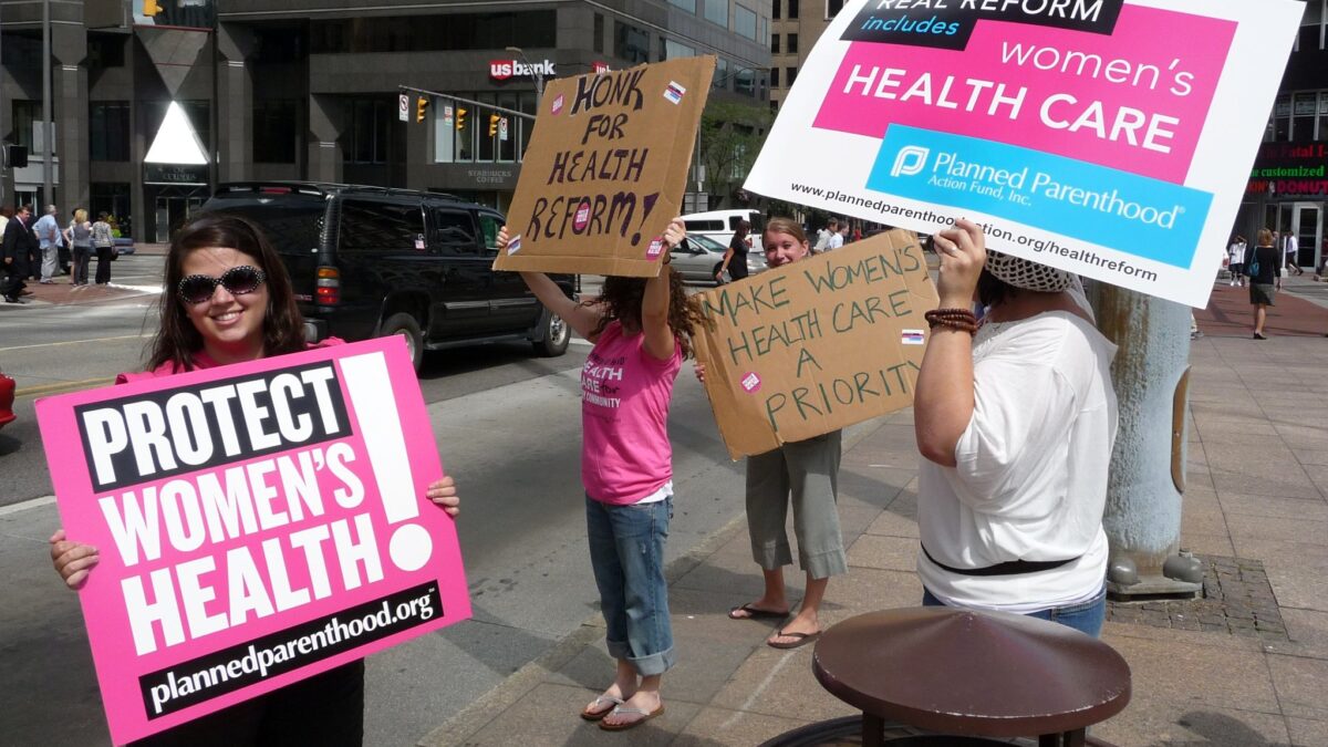 women on sidewalk holding abortion protest signs