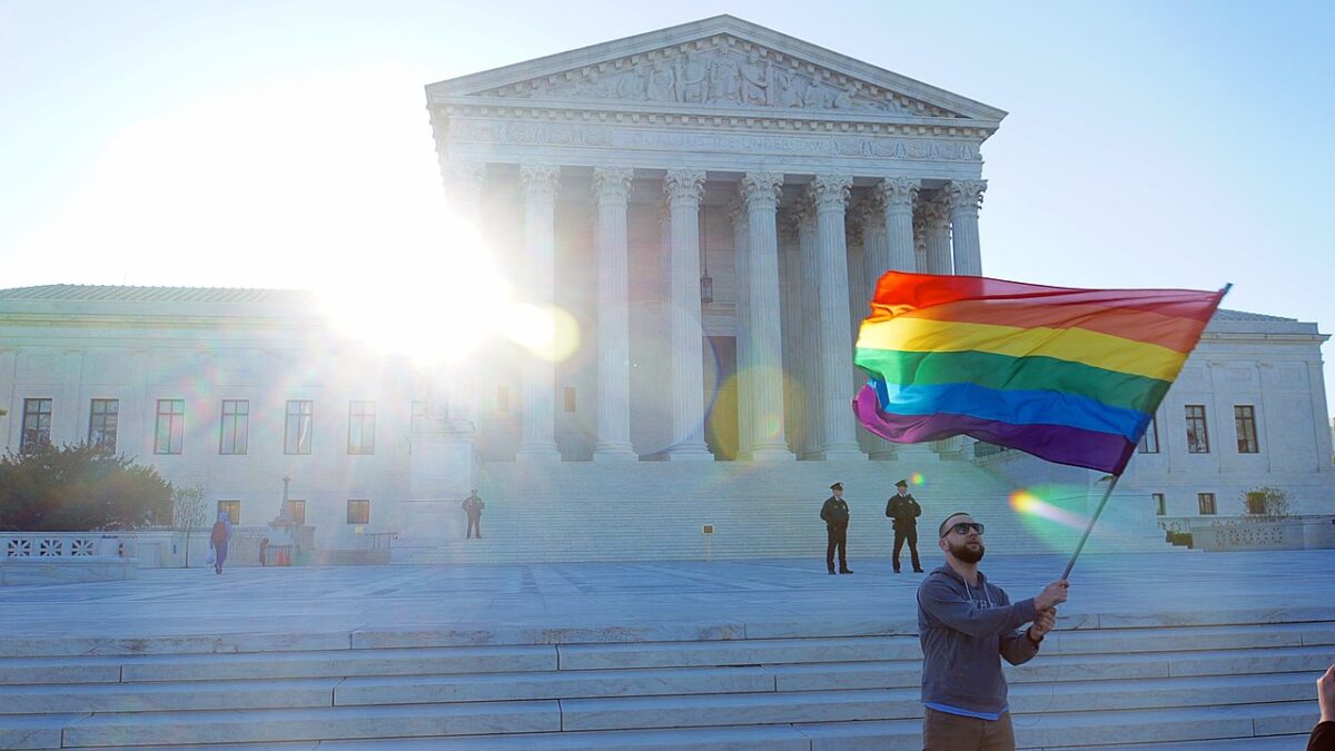 man waving gay pride flag in front of Supreme Court building