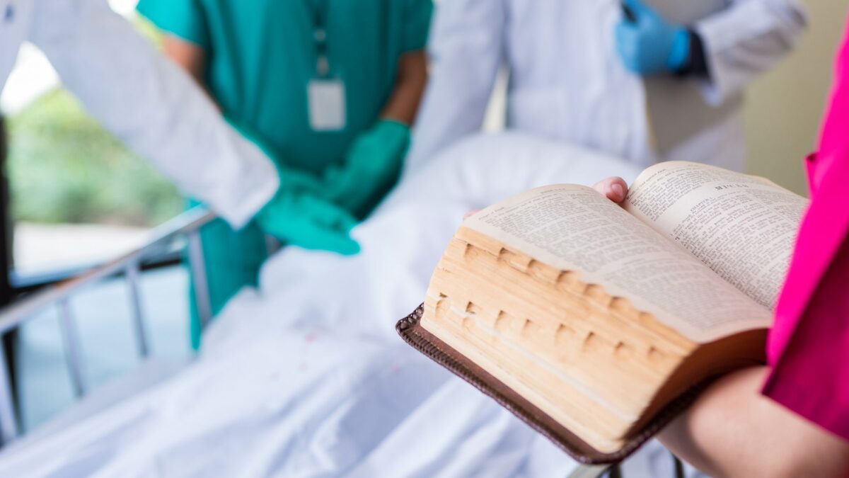 chaplain holding an open bible with hospitals and doctors in the background