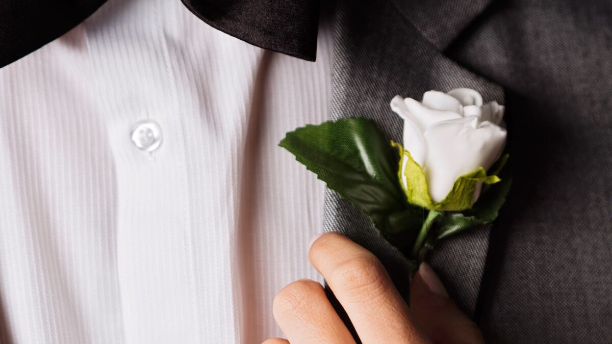 white rose Boutonniere pinned on a tux
