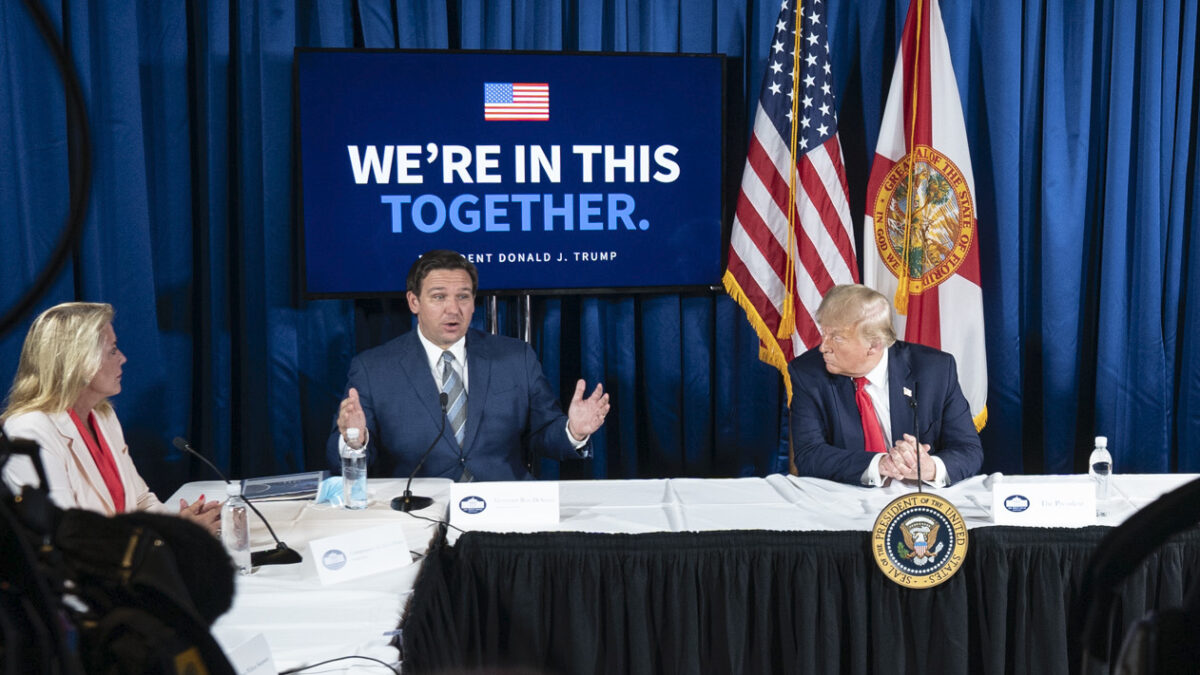 DeSantis and Trump talking from behind a table at a Covid press conference