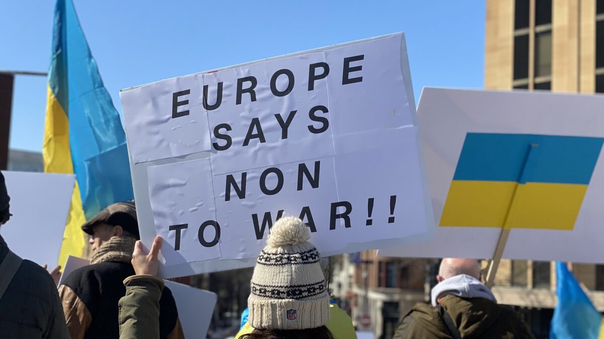 protesters outside holding anti-war signs and Ukrainian flags