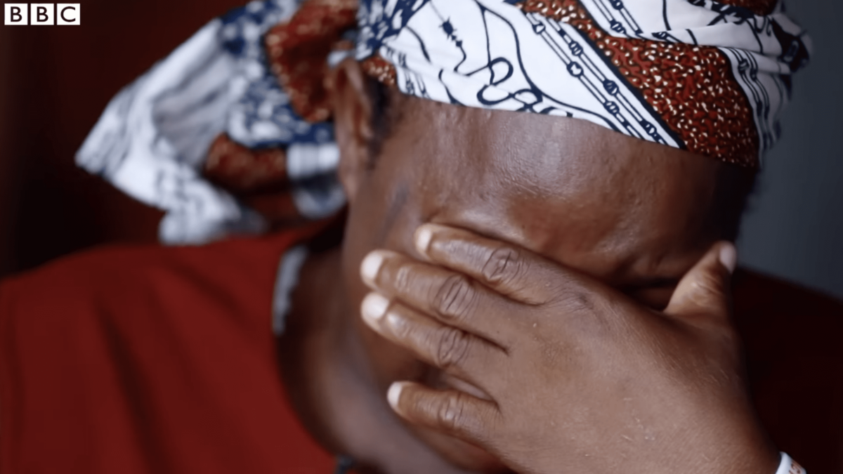 black Nigerian woman crying into hand