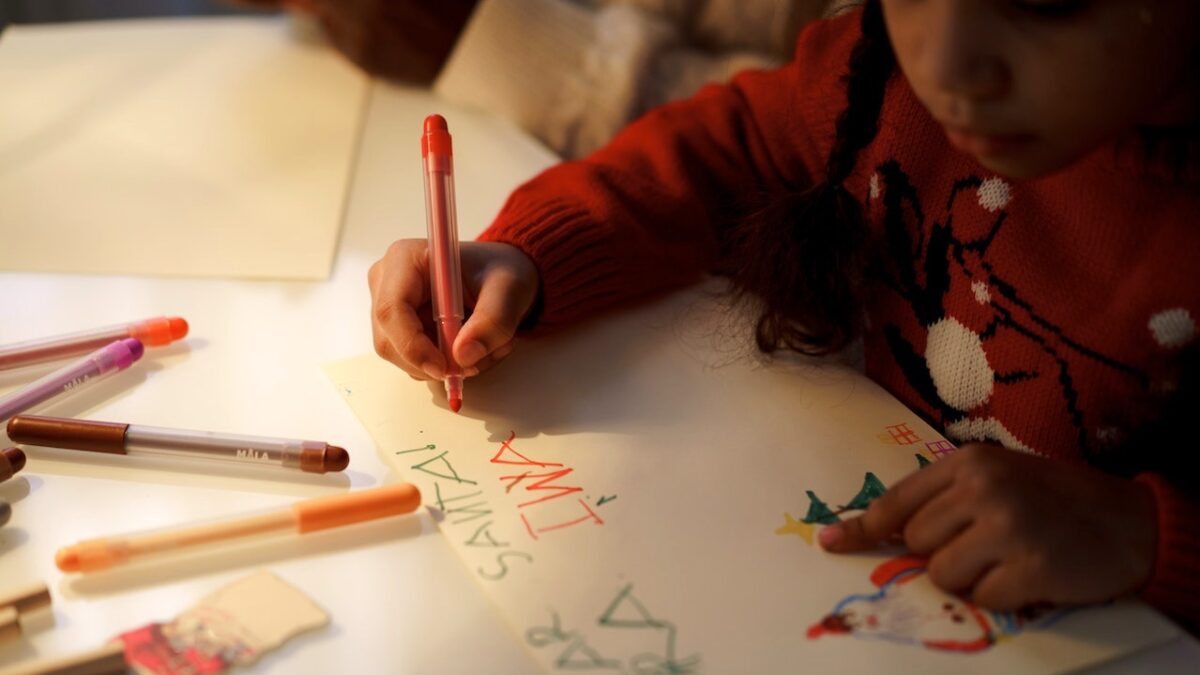 girl writing letter to santa claus in colorful pens