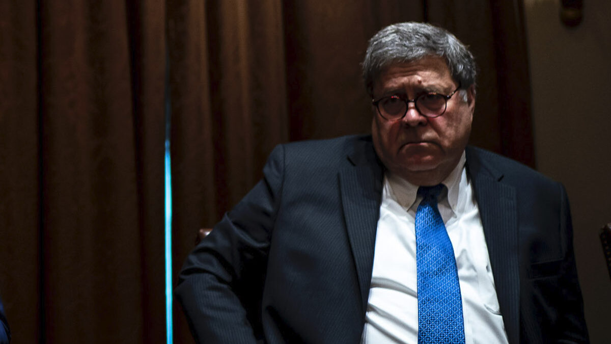 Bill Barr sitting at a table in a dark room