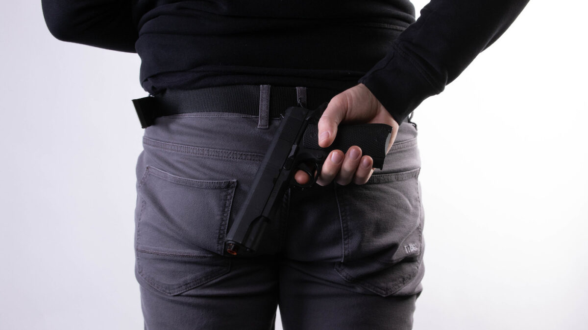 man holding a small gun behind his back