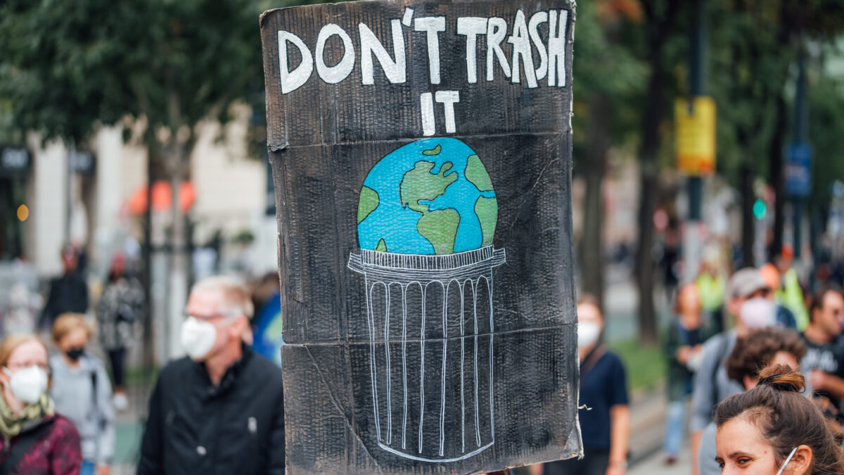 Protester holding a sign with the message "Don't trash it" and a drawing of the Earth in a trash can